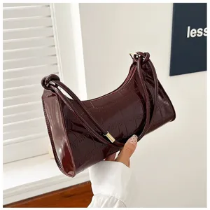 Detail of a glossy burgundy underarm bag featuring an elegant stone pattern leather texture