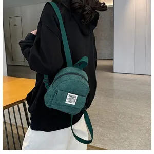 Back view of a woman wearing a forest green corduroy mini backpack for daily outdoor use