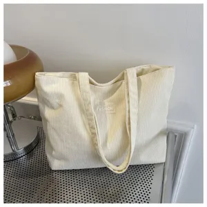 Primer plano detallado del bolso de pana crema con etiqueta minimalista Fashion