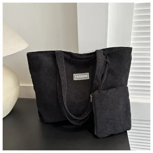 Conjunto de bolso tote de pana negra con pequeño neceser a juego en un entorno minimalista