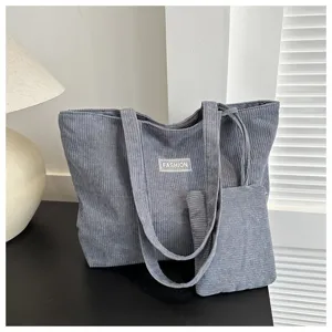 Detalle de un gran bolso tote de pana azul con una pequeña cartera a juego en un ambiente interior