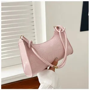 Detailed close-up showing a stylish pink crocodile embossed underarm bag held in hand