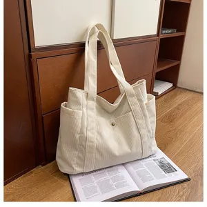 Borsa tote in velluto a coste bianca su una rivista in un ambiente domestico caldo