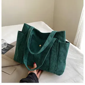 Dettaglio di una borsa tote in velluto a coste verde scuro con texture e tasche