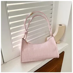 Detail of light pink underarm bag featuring elegant crocodile embossed texture pattern.