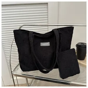 Vista detallada de un bolso tote de pana negro con un neceser a juego en el estante