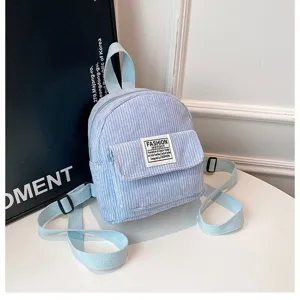 Detailed macro view of a light blue corduroy mini backpack on a white table.