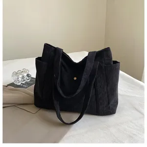 Vista dettagliata della borsa tote in velluto a coste nero con bottone dorato