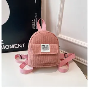 Detailed view of a stylish pink corduroy mini backpack on a minimalist white table