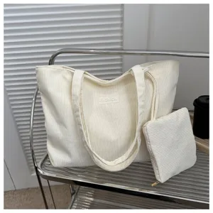 Primer plano de un bolso tote de pana blanco crema con un pequeño neceser a juego.
