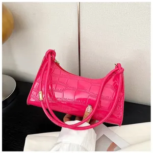 Detail shot of a hot pink croc-embossed underarm bag with elegant gold hardware
