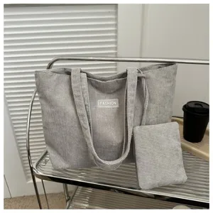 Vista detallada del bolso tote de pana gris con estuche a juego y etiqueta de moda