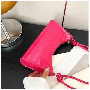 Detailed macro view of vibrant hot pink croc-effect underarm bag with knotted straps