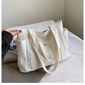 Dettaglio ravvicinato della borsa tote in velluto a coste bianco con tasca laterale utile.