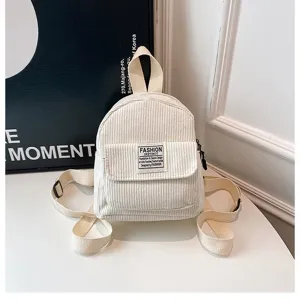 Close-up of off-white corduroy mini backpack with a 'Fashion Instinct' woven label