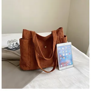 Grande borsa tote in velluto a coste marrone accanto a un tablet che mostra la sua capienza