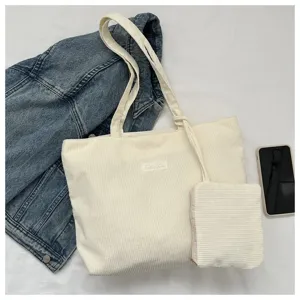 Detalle de bolso tote de pana beige que muestra la textura y el pequeño neceser a juego.