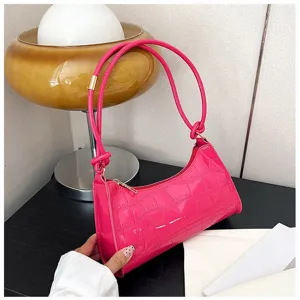 Close-up of bright pink croc-pattern underarm bag with knot strap detail