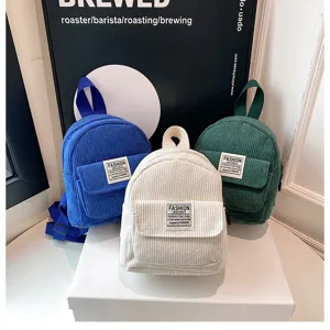 Detailed macro view of stylish mini corduroy backpacks in blue, white and green colors.