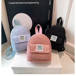 Group of three stylish corduroy mini backpacks in pink, light blue, and black tones.
