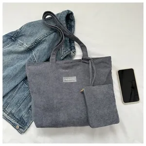 Vista detallada del bolso tote de pana gris con neceser a juego y accesorios casuales.