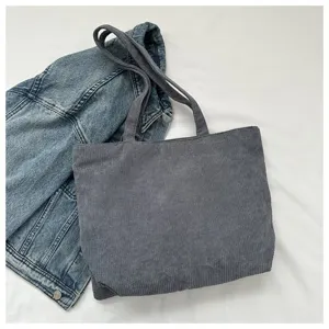 Vista detallada de un gran bolso tote de pana gris combinado con una chaqueta vaquera.