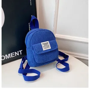 Close-up detail of a vibrant blue corduroy mini backpack featuring front pocket label
