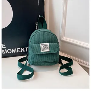 Close-up detail of a mini green corduroy backpack featuring a stylish front patch design