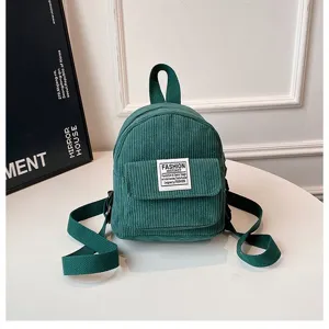 Close-up of a green corduroy mini backpack with "Fashion Instinct" patch detail