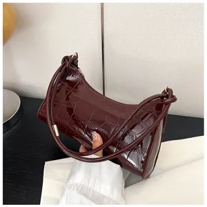 Elegant burgundy crocodile pattern underarm bag held in hand showing size and texture