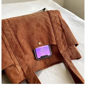 Primo piano di una borsa tote in velluto a coste marrone con trama e tasca esterna