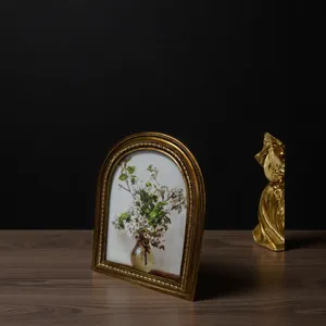 Detail view of a vintage gold arched picture frame with floral oil painting art