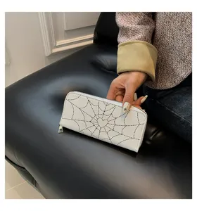 Detail view of a white long wallet with black spiderweb heart pattern design