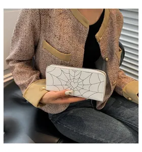 Detailed view of a white long wallet with a black spiderweb print and heart motif