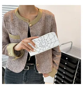 Detailed view of the white long zipper wallet with spiderweb heart print held by a model.
