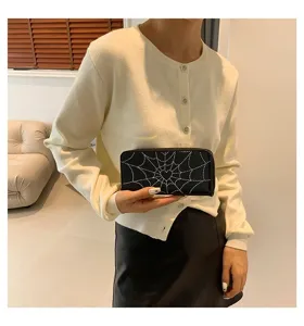 Detailed view of women's long spider web wallet held by model in modern room setting