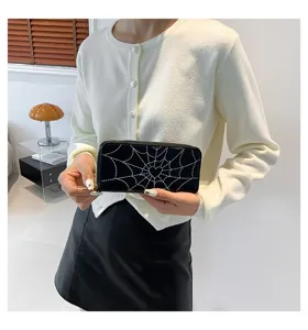 Detail view of a black long wallet with white spiderweb and heart print pattern