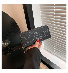 Detailed view of women's black long zip wallet featuring white heart spider web print