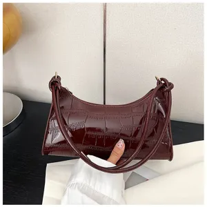 Detailed view of wine red underarm bag featuring glossy stone embossed pattern and slim straps