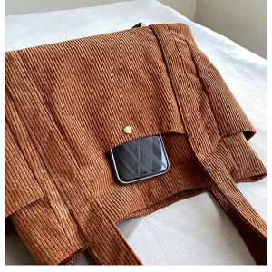 Primo piano della borsa tote in velluto a coste marrone con tasca funzionale.
