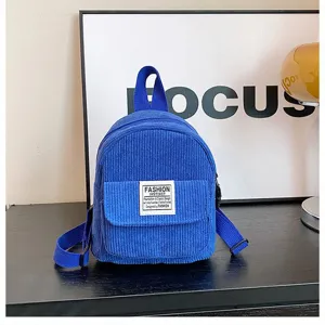 Close-up of blue corduroy mini backpack with fashion patch and adjustable straps