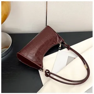 Detailed macro view of burgundy glossy stone-patterned baguette bag with knot strap