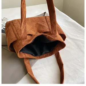 Vista dettagliata di una grande borsa tote in velluto a coste marrone con fodera.
