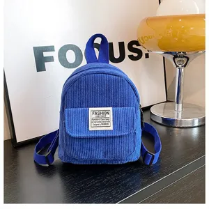 Detailed shot of a blue corduroy mini backpack featuring a stylish front label.