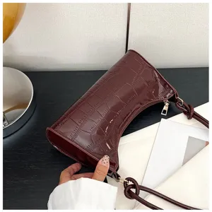 Close-up of dark brown crocodile-patterned underarm bag with gold zipper detail.