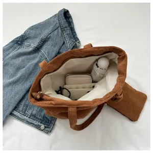 Vista detallada del amplio interior del bolso tote de pana marrón con neceser pequeño