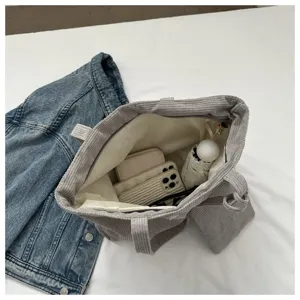 Vista interior espaciosa de un bolso tote de pana gris que muestra su gran capacidad.