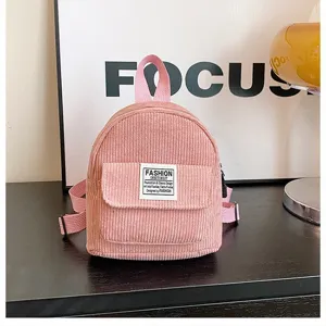 Detail view of a pink corduroy mini backpack with a front pocket and label