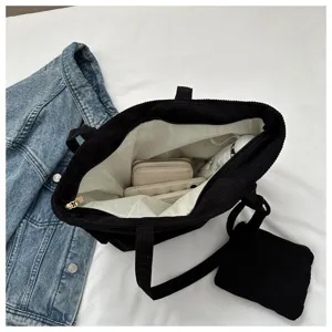 Vista interior del bolso tote de pana negra que muestra gran capacidad y forro blanco