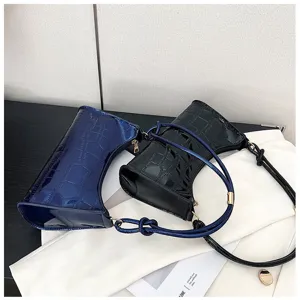 Close-up of glossy faux crocodile pattern underarm bags in blue and black colors